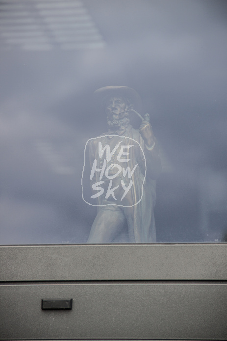 Leineweberfigur hinter Fensterscheibe