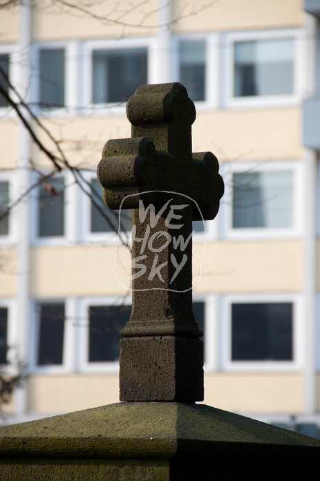Grabkreuz vor Hochhaus