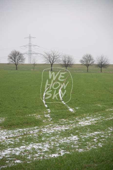 Schneespuren auf grünem Acker