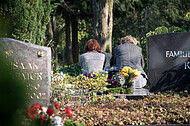 Trauernde zwischen Grabsteinen
