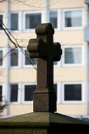 Grabkreuz vor Hochhaus